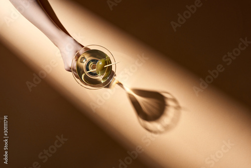 Foto Cropped view of woman holding glass of martini on beige background