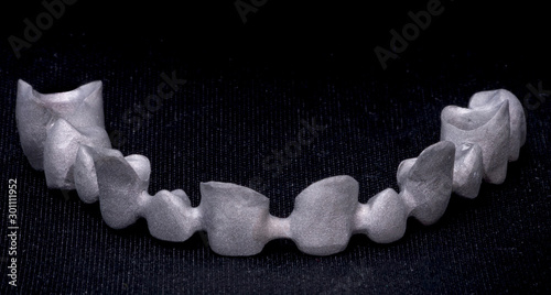 Metal frame of ceramic-metal bridge. Cermet bridge denture. Closeup dental photo on black background, isolate.
