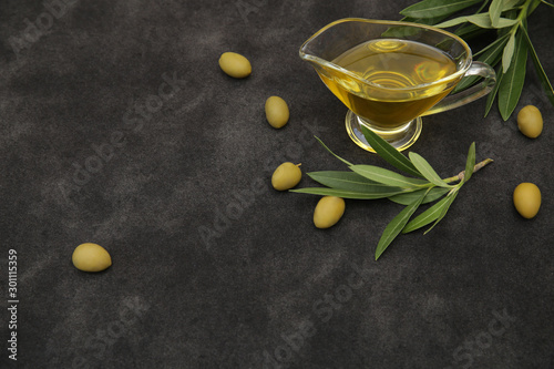 Organic Extra virgin olive oil in a glass and olive branch with leaves on a black background. Healthy food. Mediterranean diet. Pattern, poster, food background. With copy space. Top View.