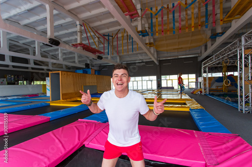 Fitness, fun, leisure and sport activity concept - Handsome happy man jumping on a trampoline indoors