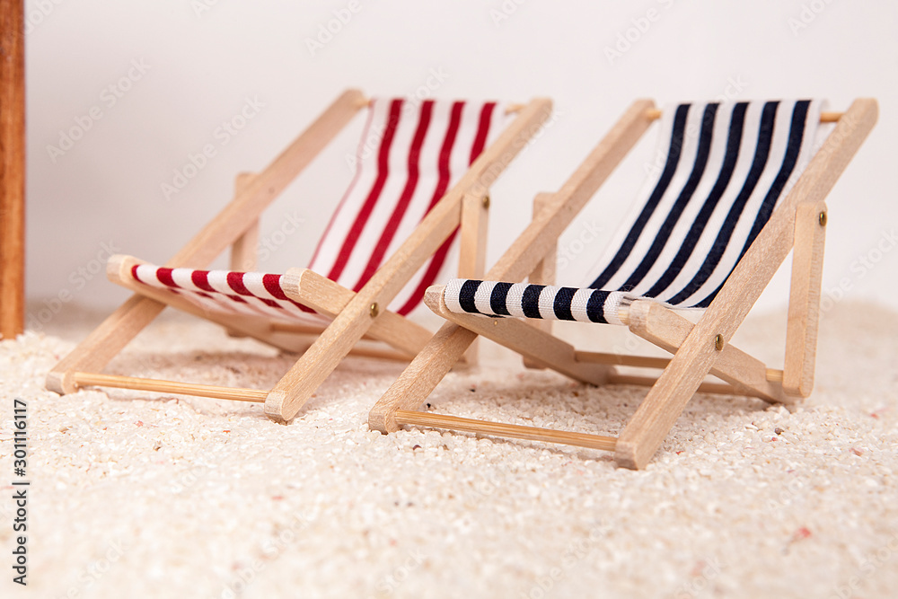 Toy chaise longue on sandy beach on white background. Relaxation concept. Toy chaise longue on sandy beach on white background. Relaxation concept.
