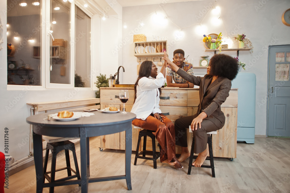 Three african american friends spending time at kitchen with wine. Black peoples relaxing at home. Three african american friends spending time at kitchen with wine. Black peoples relaxing at home.