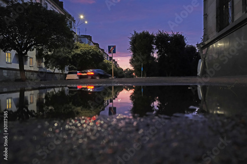 Low shot of puddle whilst it rains with traffic