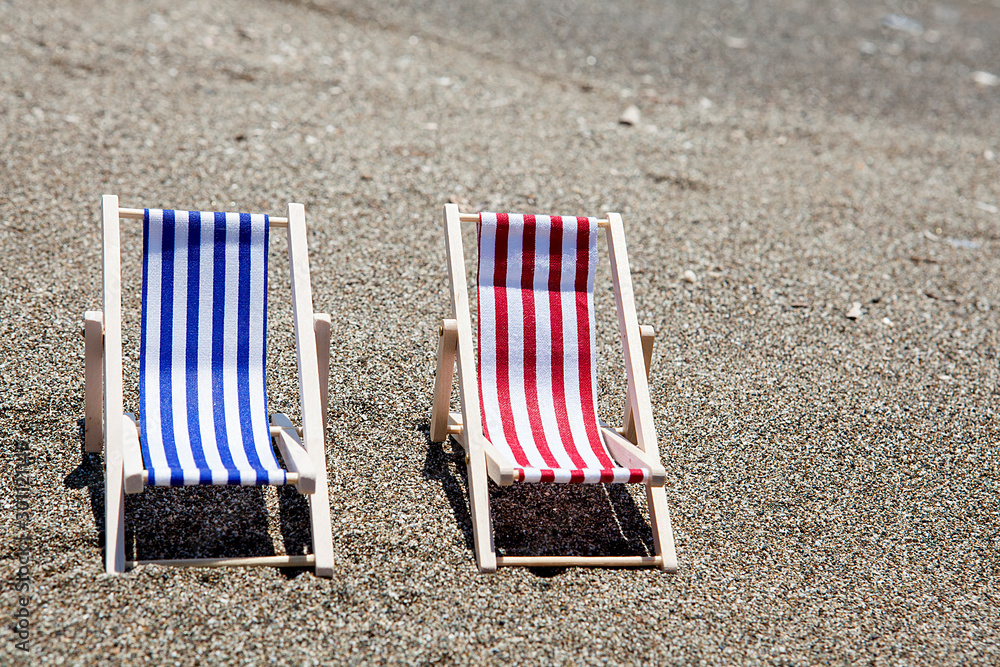 Toy chaise longue on sandy beach on sunny day at the white background. Relaxation concept. Toy chaise longue on sandy beach on sunny day at the white background. Relaxation concept.