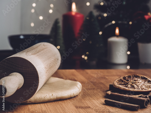 roll out the cookies dough with a rolling pin. Home Pastry preparation on Christmas time. traditional Christmas cookies with cinnamon and spice. candles and christmas trees on background