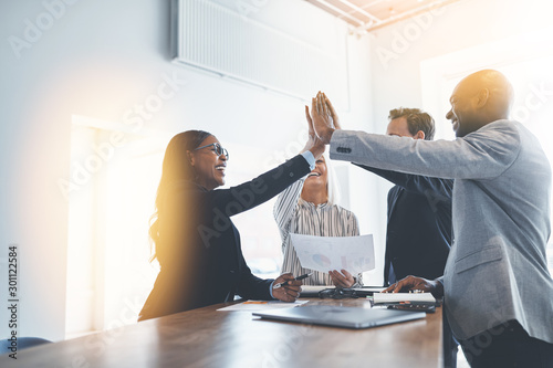 Diverse group of businesspeople high fiving together in an offic photo