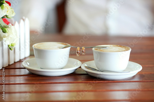 Bride and groom's Coffee time, coffee break.Cups and rings on teaspoon in cafe