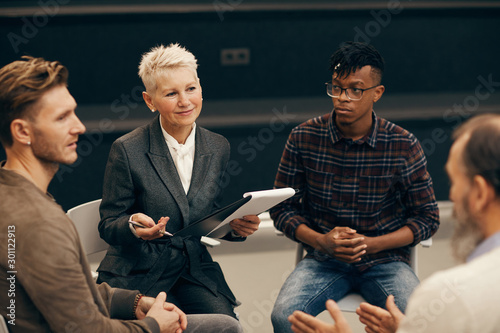 Group of business people sitting and discussing future plans with mature woman during meeting
