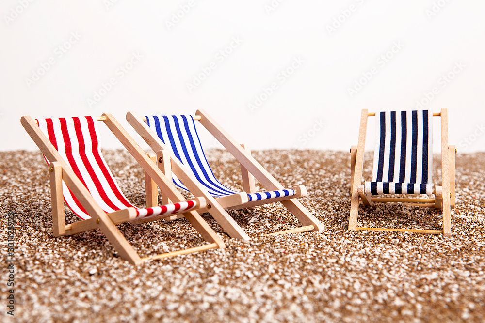 Toy chaise longue on sandy beach on sunny day at the white background. Relaxation concept. Toy chaise longue on sandy beach on sunny day at the white background. Relaxation concept.