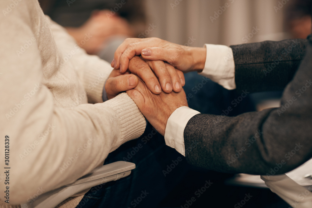Close-up of mature man and woman holding hands and supporting each other in difficult situation