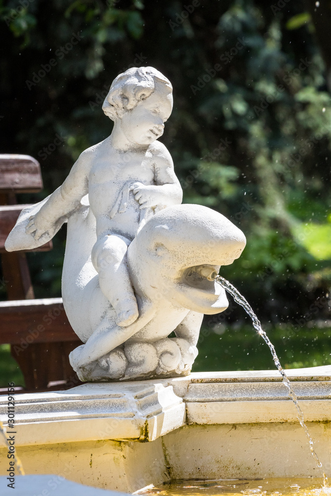 Fountain element with a sculpture of a child sitting on a dolphin