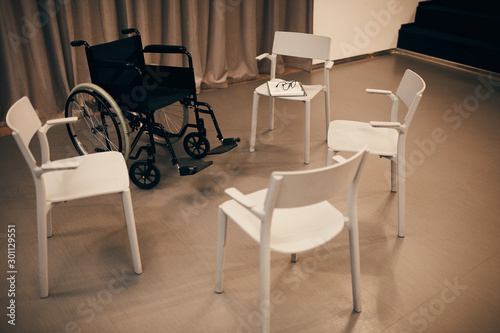 Image of empty room with white chairs and wheelchair prepared for meeting