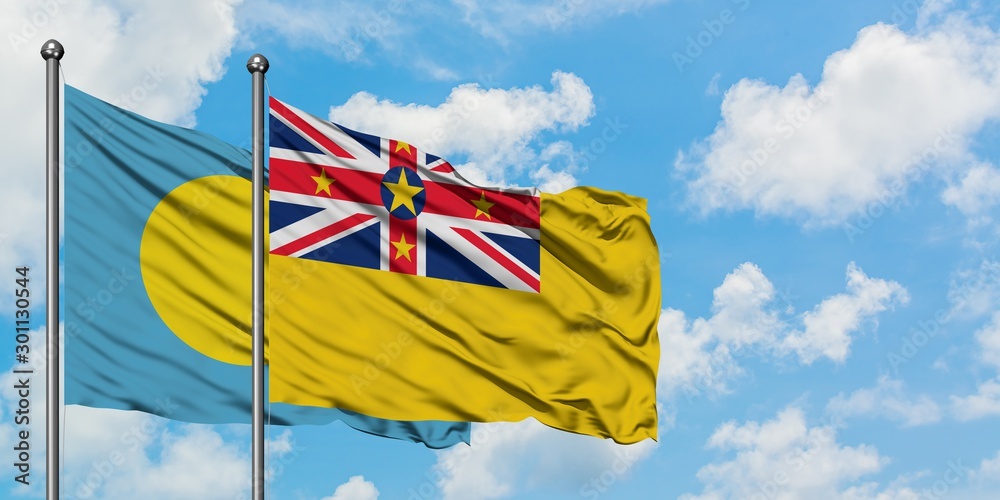 Palau and Niue flag waving in the wind against white cloudy blue sky together. Diplomacy concept, international relations.
