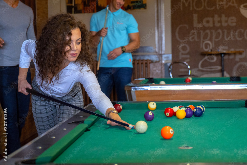 Fototapeta premium Beautiful smiling women playing billiards at a bar
