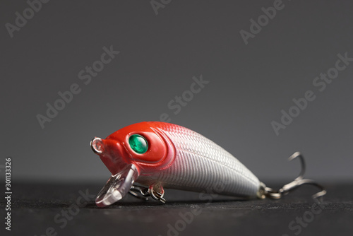 Fishing lure Wobbler closeup on gray background. Hooks and background in blur.