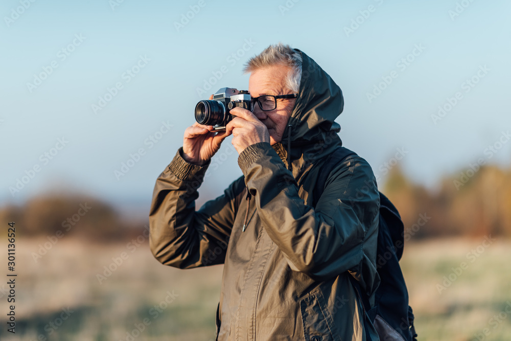 Senior man taking photo in nature. Man photographing autumn forest. Senior man taking photo in nature. Man photographing autumn forest.