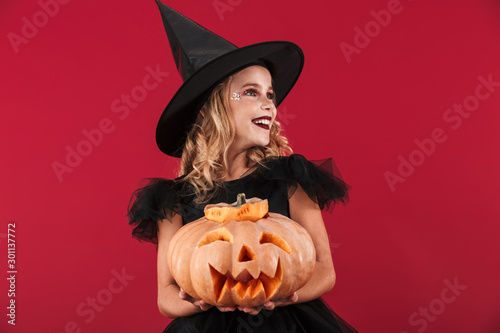 Cheerful little girl wearing Halloween witch costume