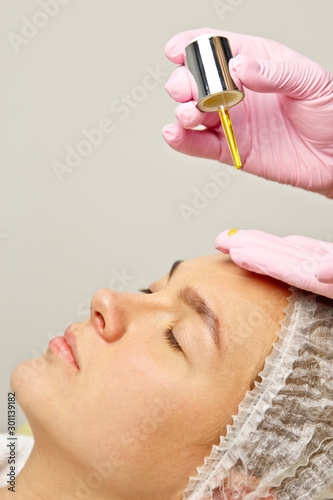 preparation for procedures in the cosmetologist s office. applying oil to moisturize the face with a special pipette. photo