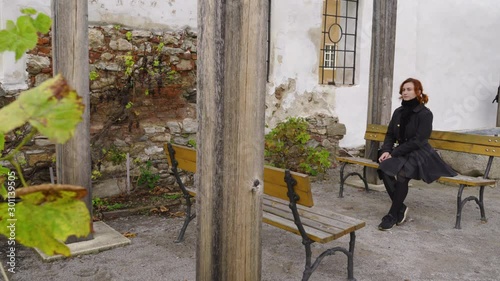 Wallpaper Mural Redhead woman sits in a monastery garden in Cesky Krumlov wearing black coat Torontodigital.ca