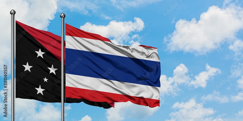 Papua New Guinea and Thailand flag waving in the wind against white cloudy blue sky together. Diplomacy concept, international relations.
