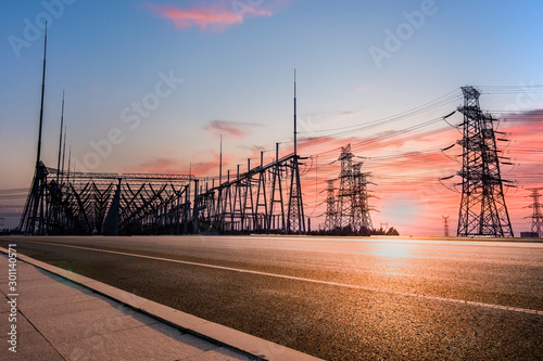 Transmission tower on asphalt road in the setting sun photo