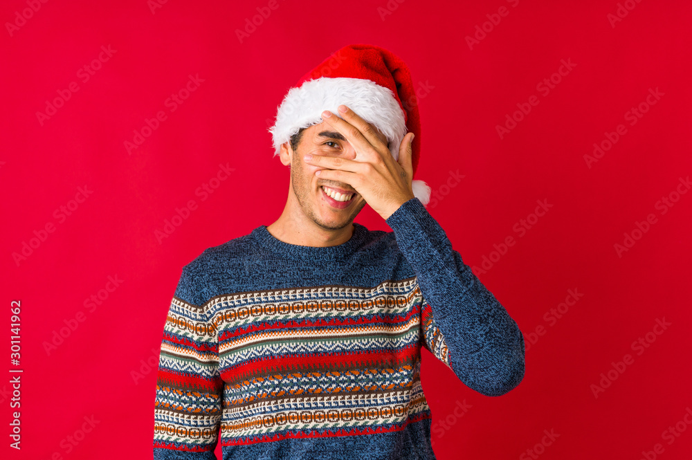 Young man on christmas day pointing with forefingers to a copy space, expressing excitement and desire. Young man on christmas day pointing with forefingers to a copy space, expressing excitement and desire.