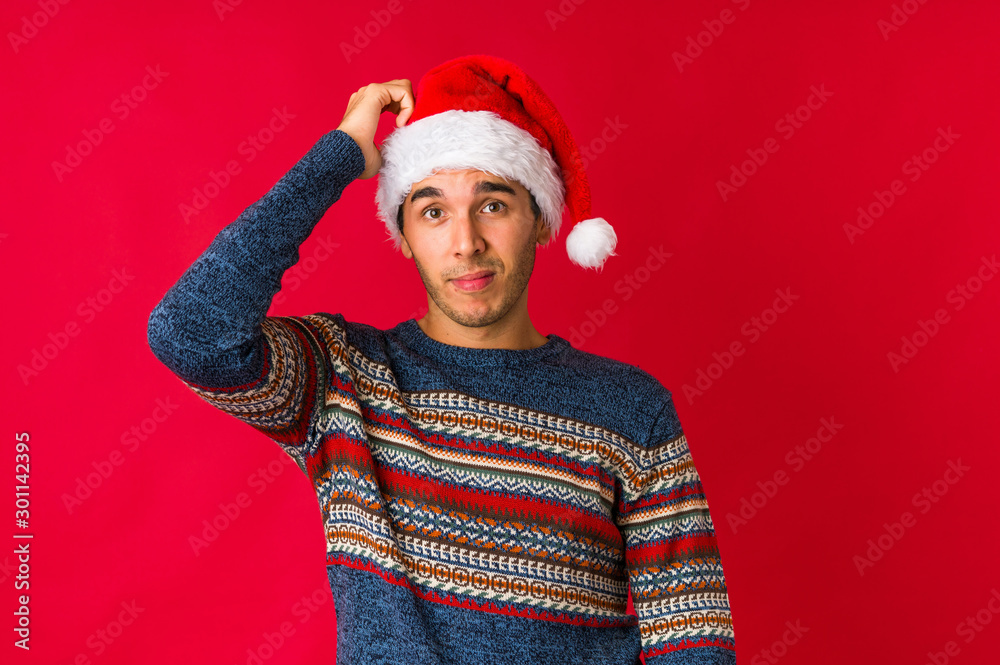 Young man on christmas day pointing temple with finger, thinking, focused on a task. Young man on christmas day pointing temple with finger, thinking, focused on a task.