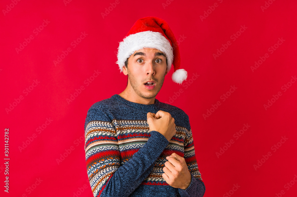 Young man on christmas day blink through fingers frightened and nervous.