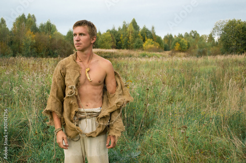 Fényképezés Downshifting concept - medieval peasant in a ragged clothes reconstruction, worl