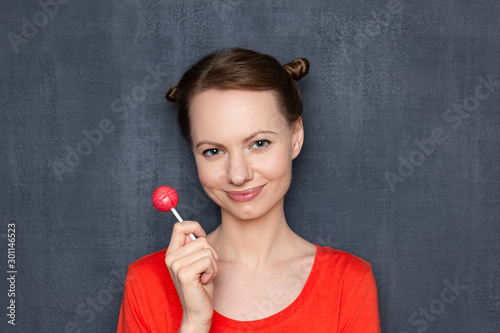 Portrait of happy pretty girl holding pink lollipop in hand
