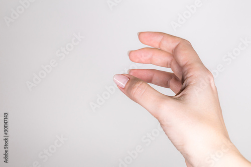Closeup point of view of outstretched female single right empty hand of white woman isolated on light grey background. Horizontal color photography.