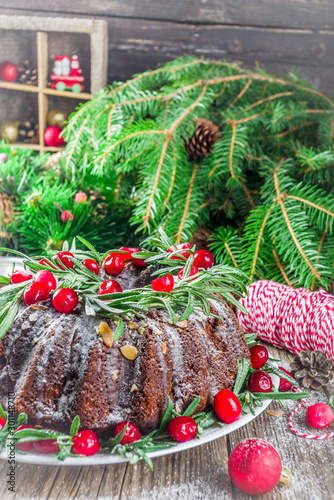 Homemade Christmas baking. Dark chocolate gingerbread christmas bundt cake with powdered sugar  fresh cranberries and rosemary  with xmas tree decoration