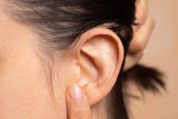 Young woman showing mole on ear close up view