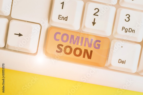 Word writing text Coming Soon. Business photo showcasing something is going to happen soon or after a short time White pc keyboard with empty note paper above white background key copy space photo