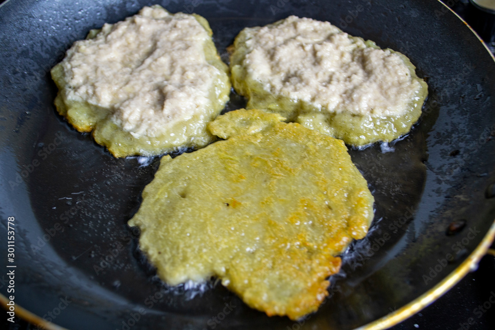 potato pancakes are fried in a pan, boiling oil potato pancakes are fried in a pan, boiling oil