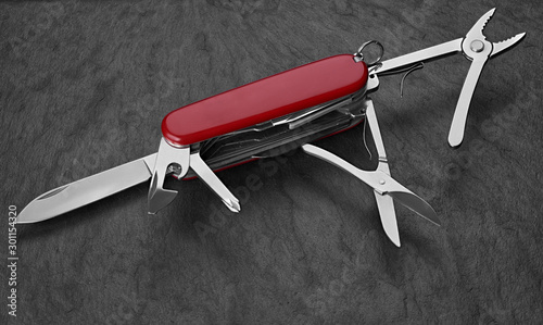 old Swiss knife on a stone background. Top view photo