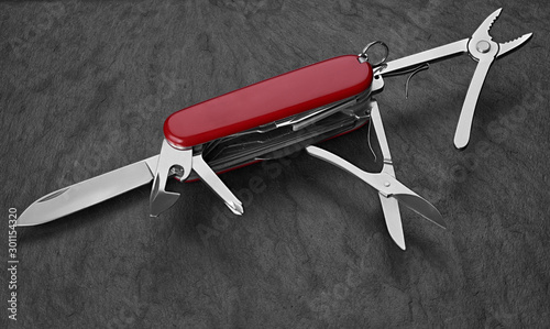 Foto old Swiss knife on a stone background. Top view