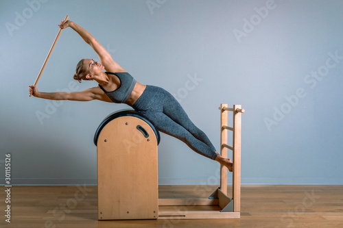 Beautiful woman doing pilates exercise, training on barrels. Fitness concept, special fitness equipment, healthy lifestyle, plastic. Copy space, sport banner for advertising. photo