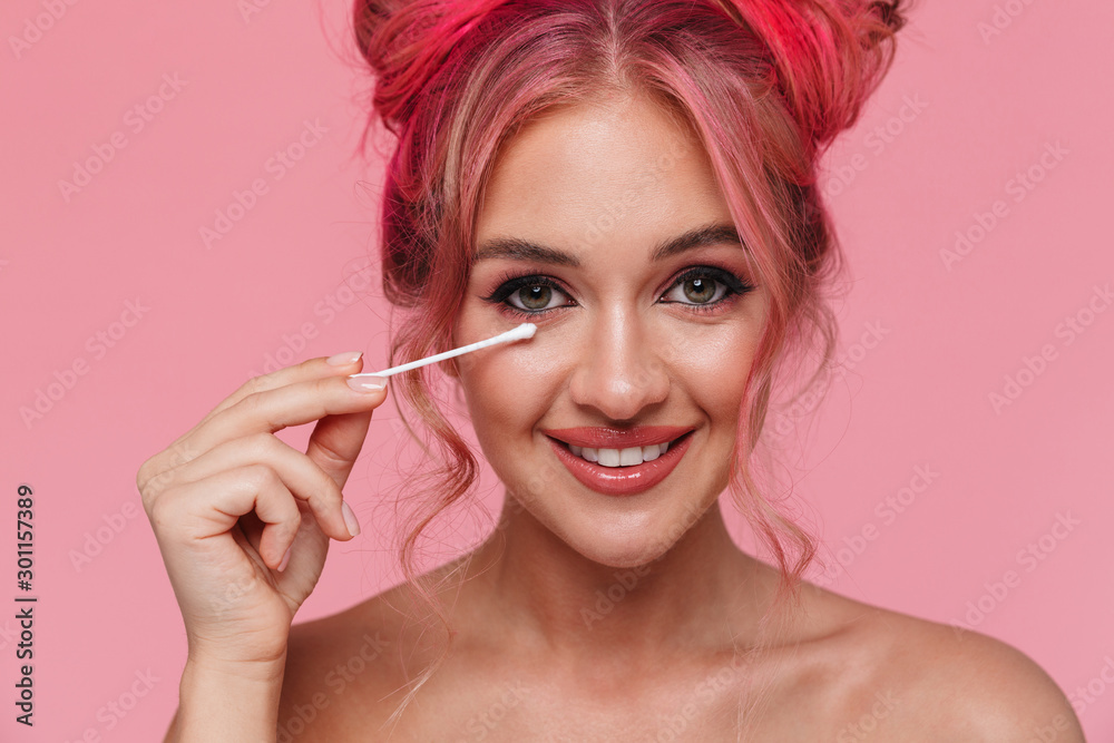Obraz premium Portrait of shirtless young woman removing her makeup with cotton swab
