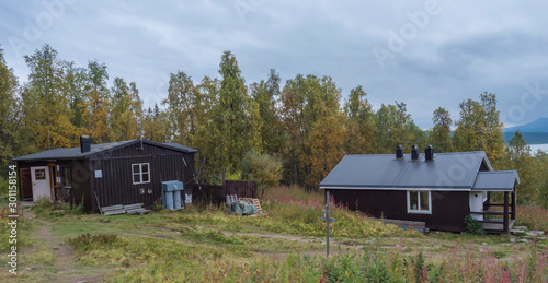 View on Aktse Fjallstuga STF mountain cabin hut at Sweden Lapland with Laitaure lake, green hills and birch tree. Cloudy rainy day on the Kungsleden Trail