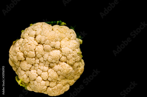 Closeup of fresh organic cauliflower on black background. Diet food concept. Vegan food. Copy space