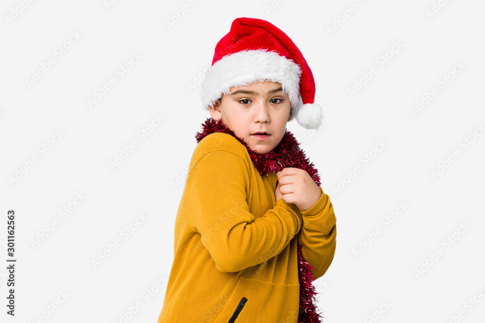 Little boy celebrating christmas day wearing a santa hat isolated scared and afraid. Little boy celebrating christmas day wearing a santa hat isolated scared and afraid.