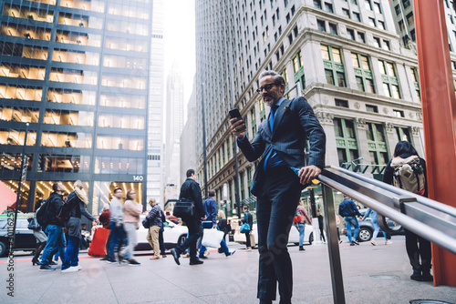 Quadro em tela Businessman in crowded street with smartphone in hand