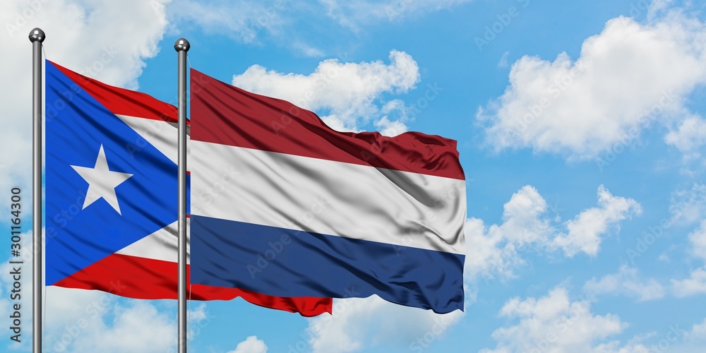 Puerto Rico and Netherlands flag waving in the wind against white cloudy blue sky together. Diplomacy concept, international relations.