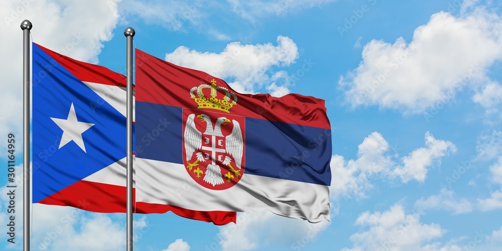Puerto Rico and Serbia flag waving in the wind against white cloudy blue sky together. Diplomacy concept, international relations.