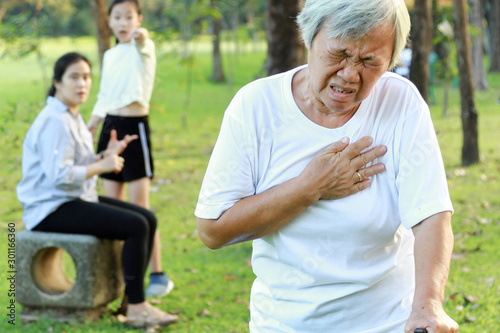 Asian elderly people having heartbeats fast,difficulty breathing,symptoms of heart problem while walking exercise in outdoor park,senior woman with chest pain suffer from heart attack,health care