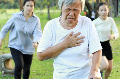 Asian elderly woman having difficulty breathing suffer from heart attack,heart problem while walking exercise at park, daughter and granddaughter are running to help,senior mother feeling chest pain © Satjawat