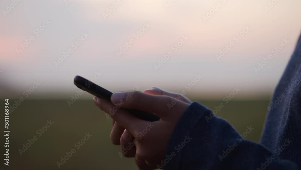 Close up shot Hand of little girl using smart phone on  meadow in the sunset on blurred background