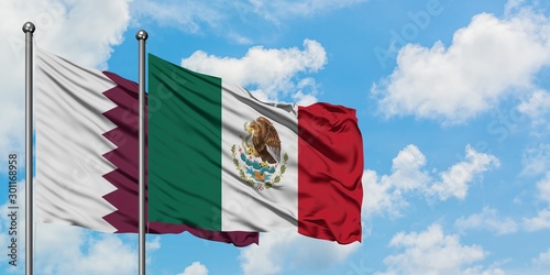 Qatar and Mexico flag waving in the wind against white cloudy blue sky together. Diplomacy concept, international relations.
