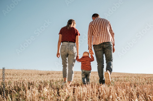 Happy Young Family Mom and Dad with Their Little Son Enjoying Summer Weekend Picnic Outside the City in the Field at Sunny Day Sunset, Vacation Time Concept